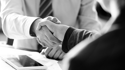 two people dressed in business attire shaking hands