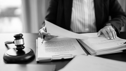 one person sitting at a desk and looking over a stack of paperwork. There is a judges gavel on the desk next to them.